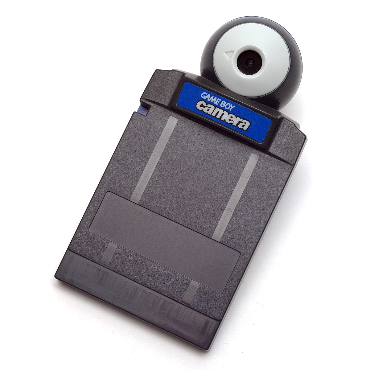 A blue gameboy camera cartridge, it is a small rectangular box of plastic with a spherical enclosure on one side that houses a camera.