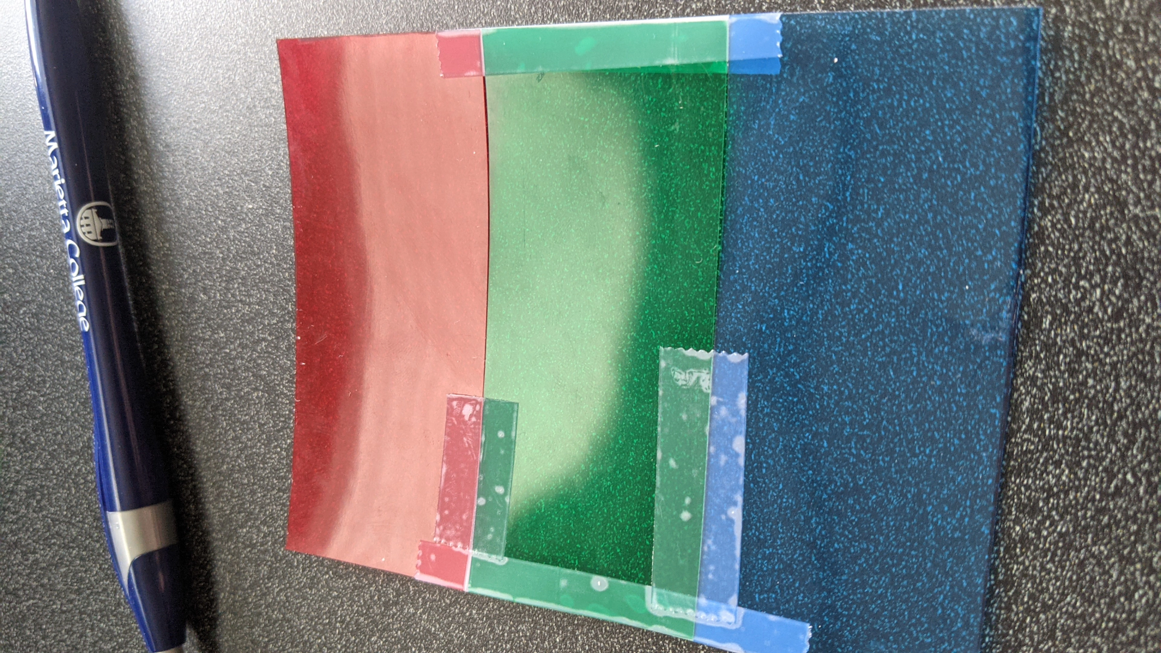 Three small colored pieces of plastic taped together in strips