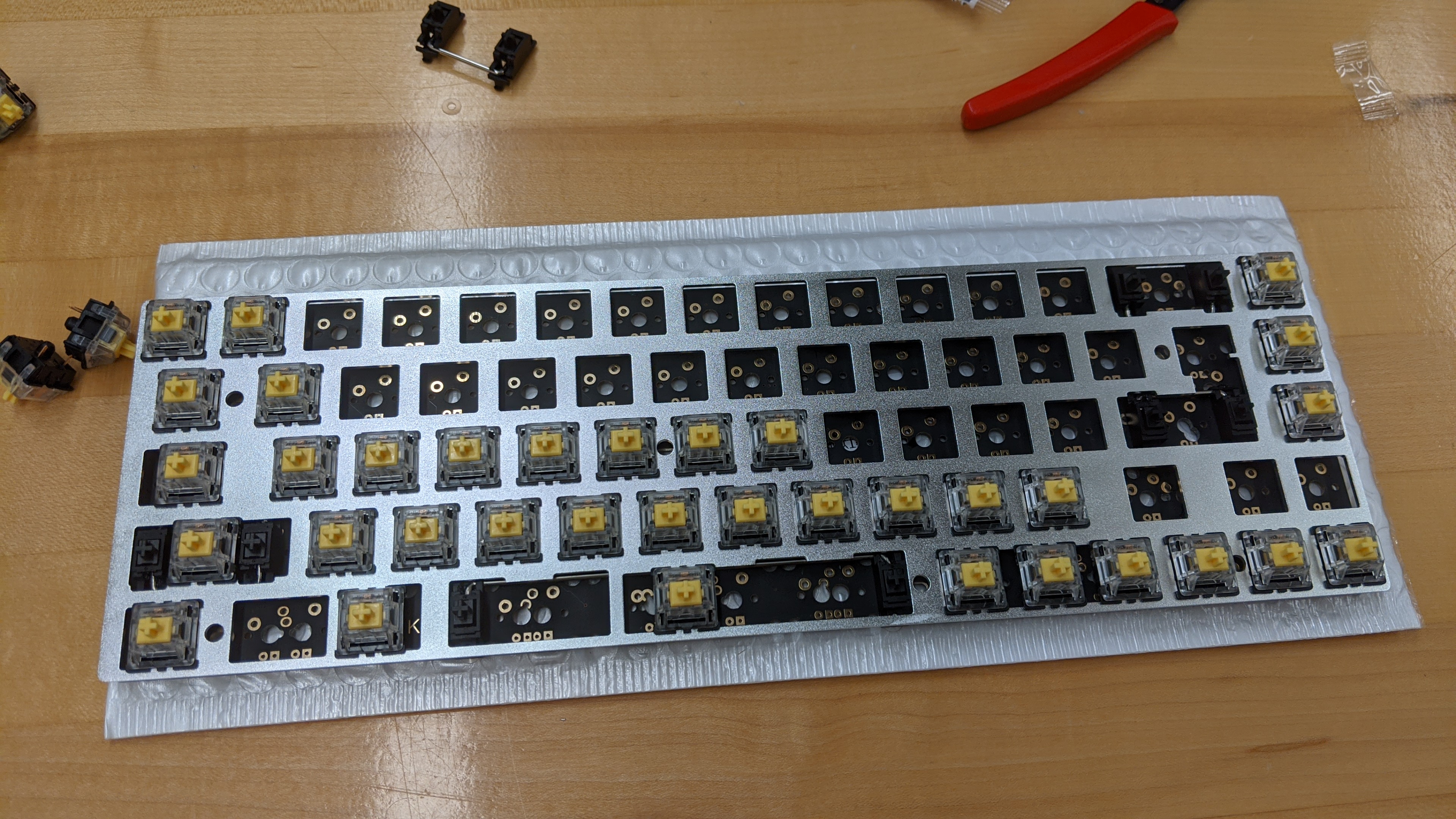 A partially assembled keyboard, sitting on a desk. The circuit board and switches are completely exposed, and it has no case.