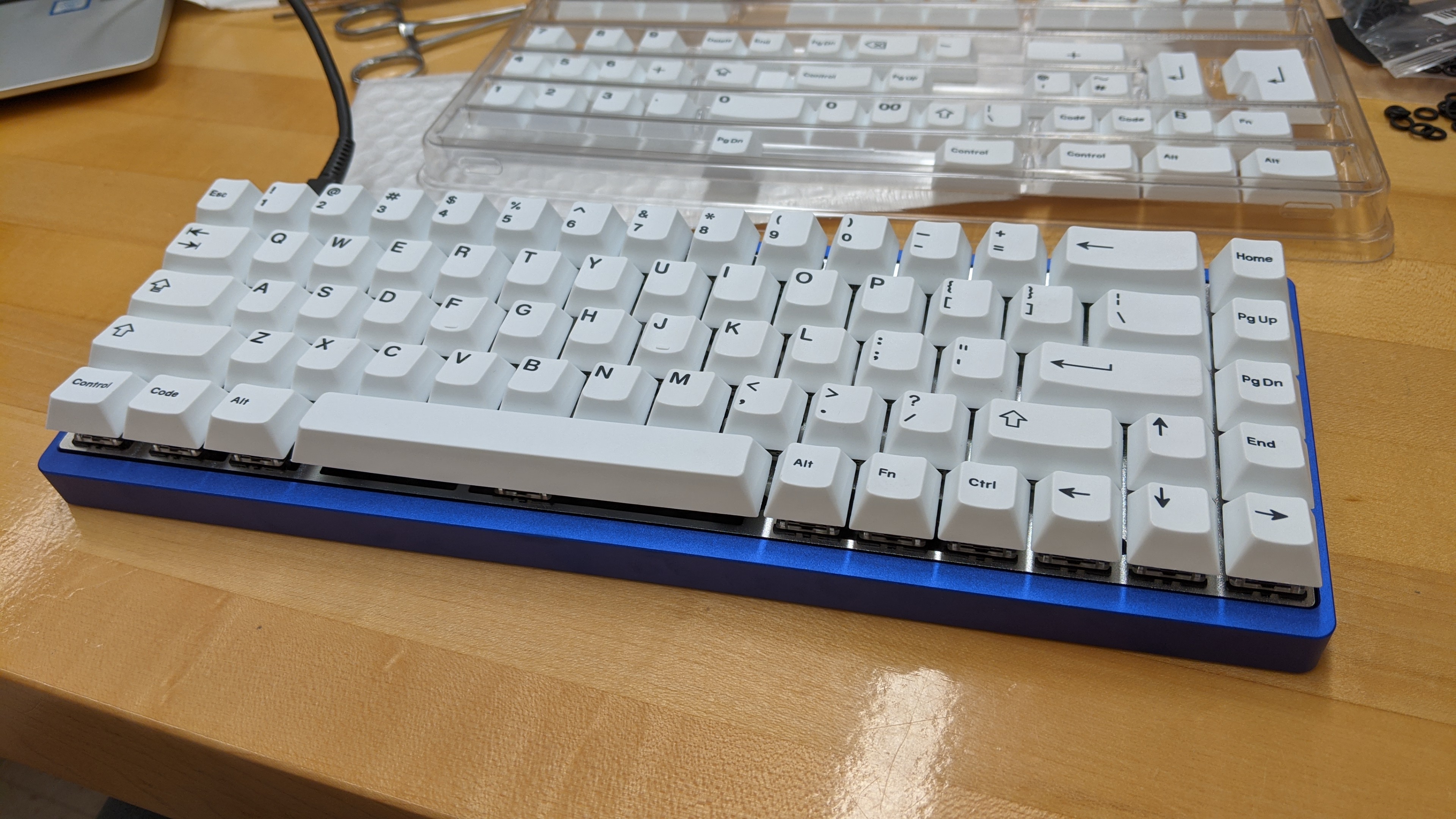 The keyboard, fully assembled. It has a blue case, white keys and black legends.