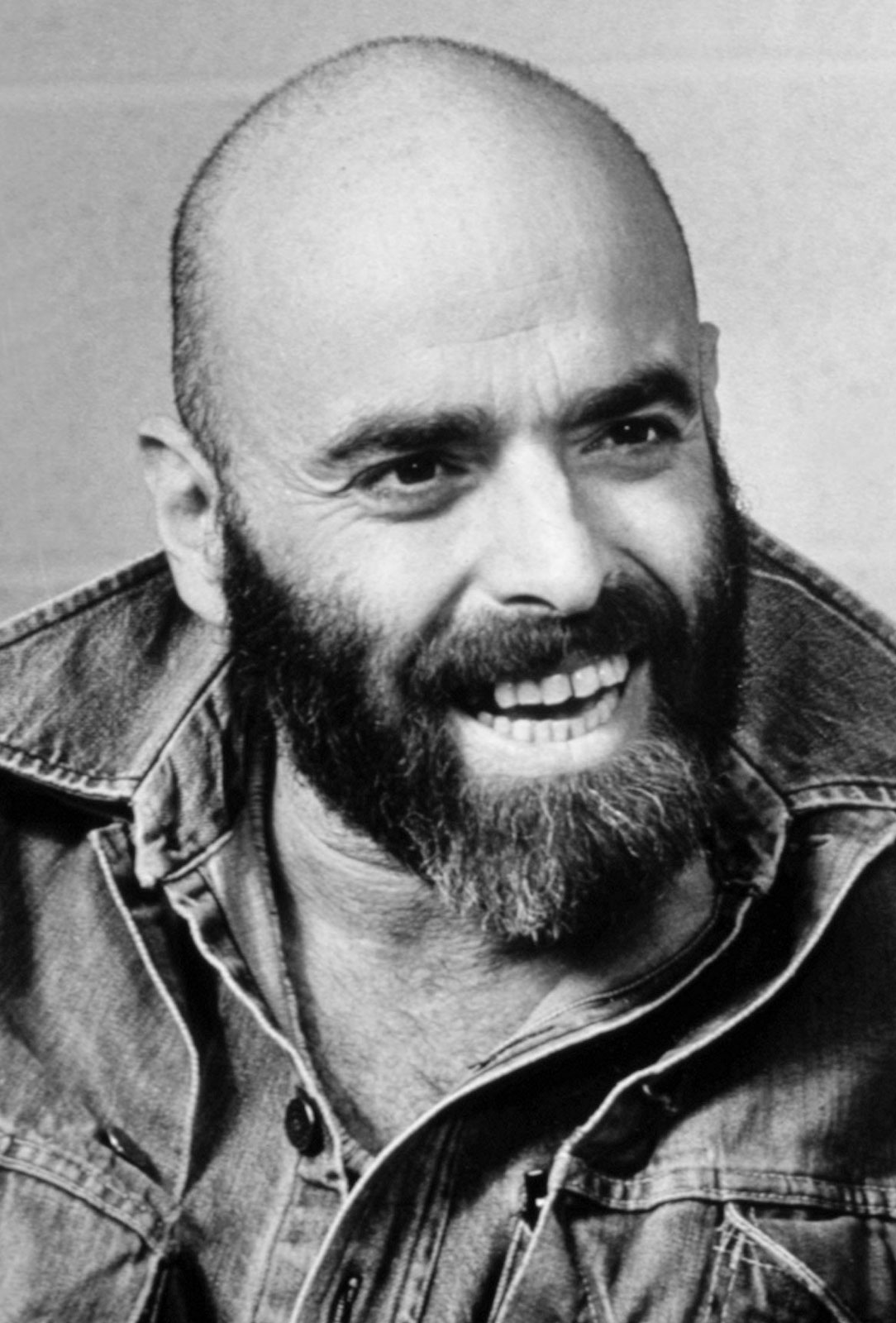 A black and white picture of Shel Silverstein. He has a bald head with thick eyebrows and a bushy beard.